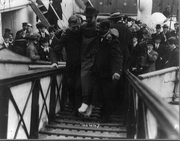Harold Bride, surviving wireless operator of the TITANIC, with feet bandaged, being carried up ramp of ship